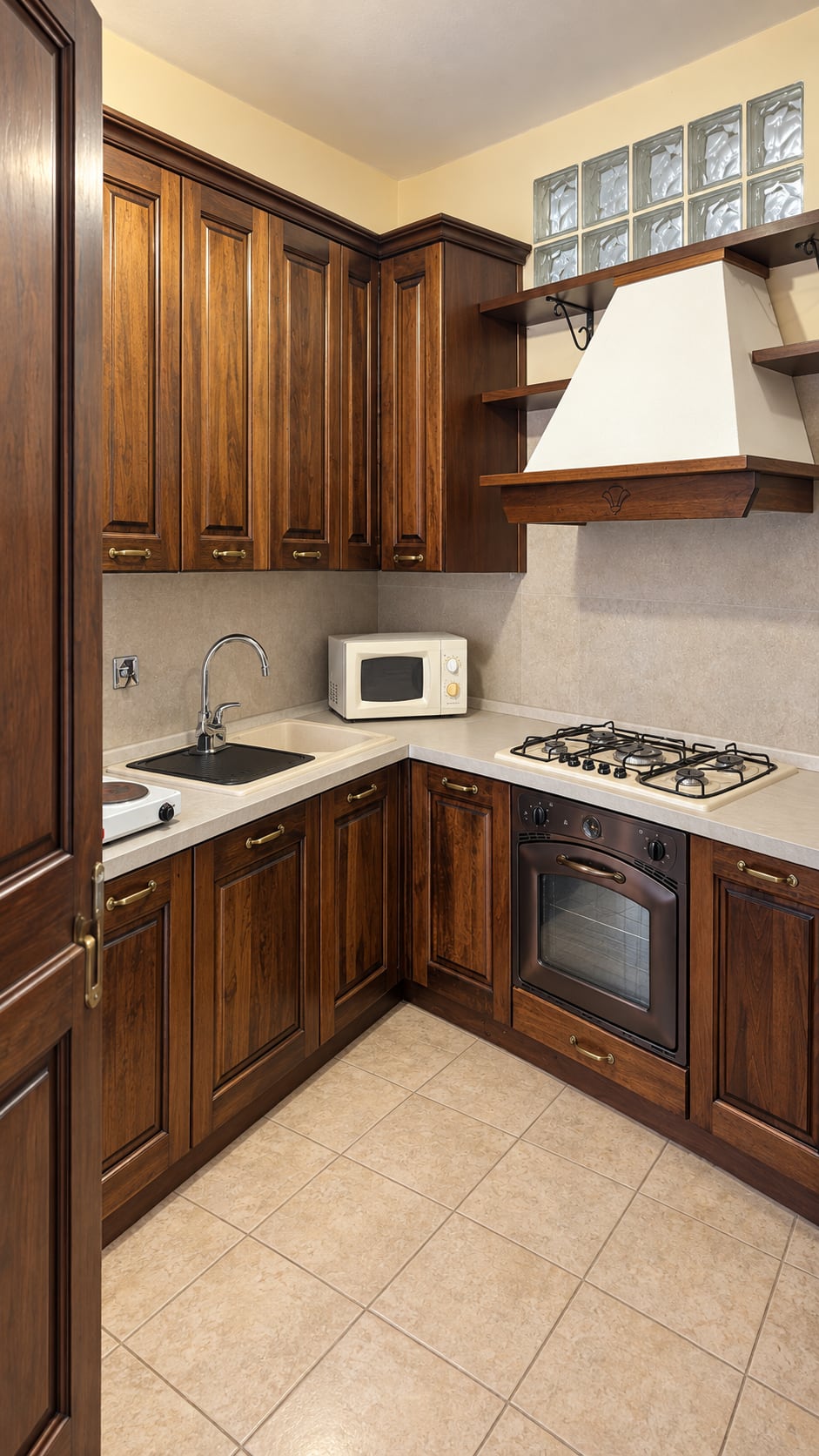 Cucina ad angolo con mobili in legno scuro, piano cottura a gas, forno e microonde
